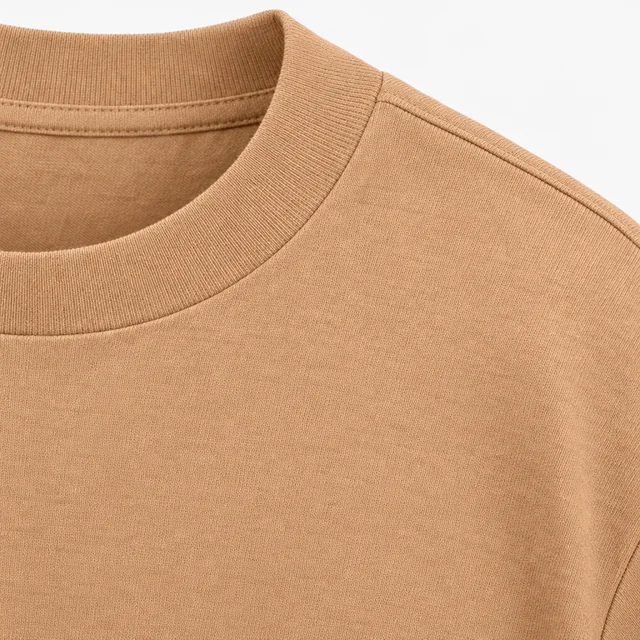 Close-up of the ribbed collar and shoulder seam of a tan T-shirt in dense jersey